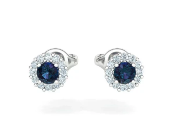 A pair of custom-made stud earrings with bright, sparkling sapphires in a classic round cut, mounted in a sleek gold setting, displayed on a dark, elegant jewelry box.