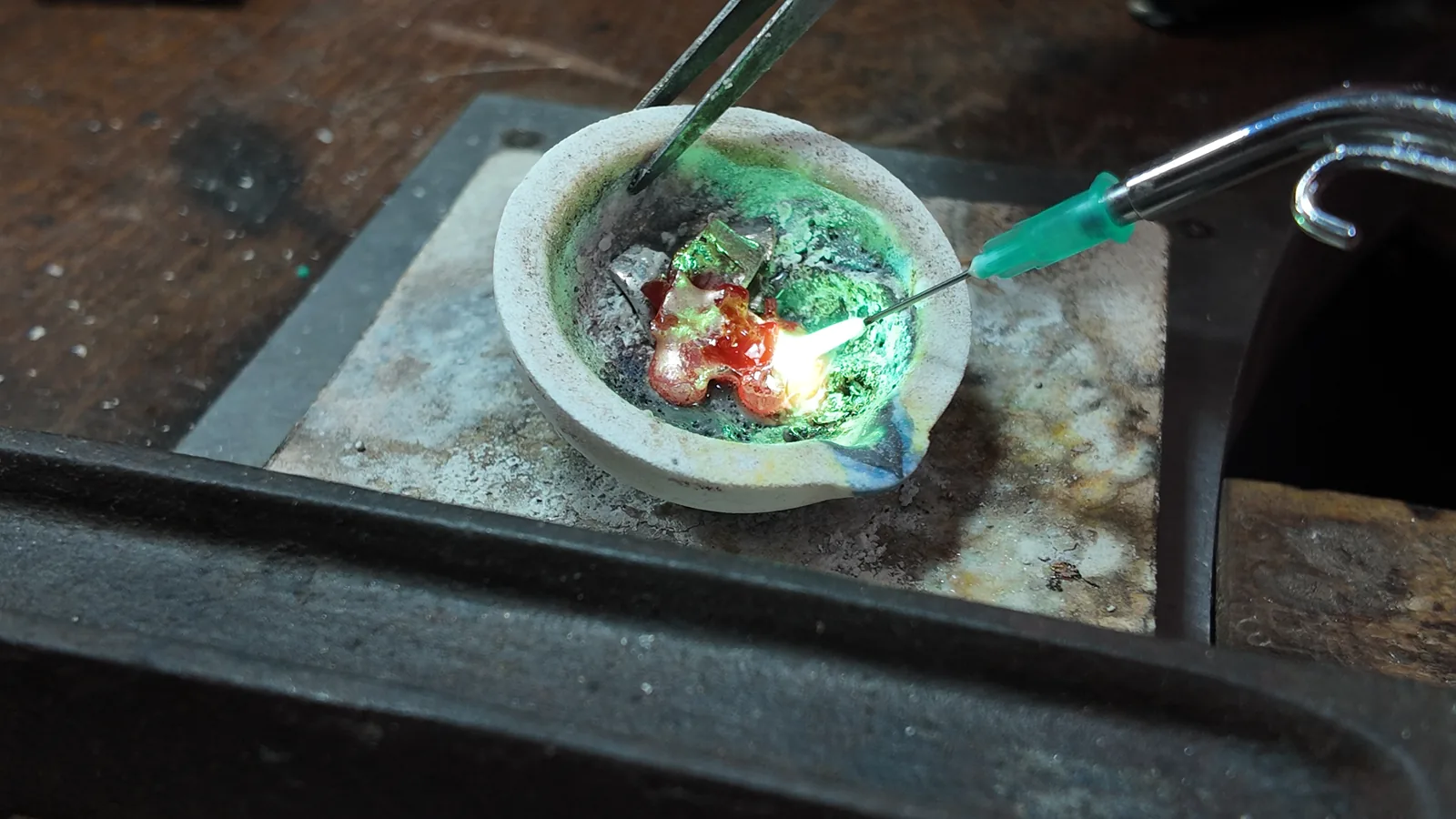 Metal pieces heated with a torch in a ceramic crucible at Bamina’s workbench