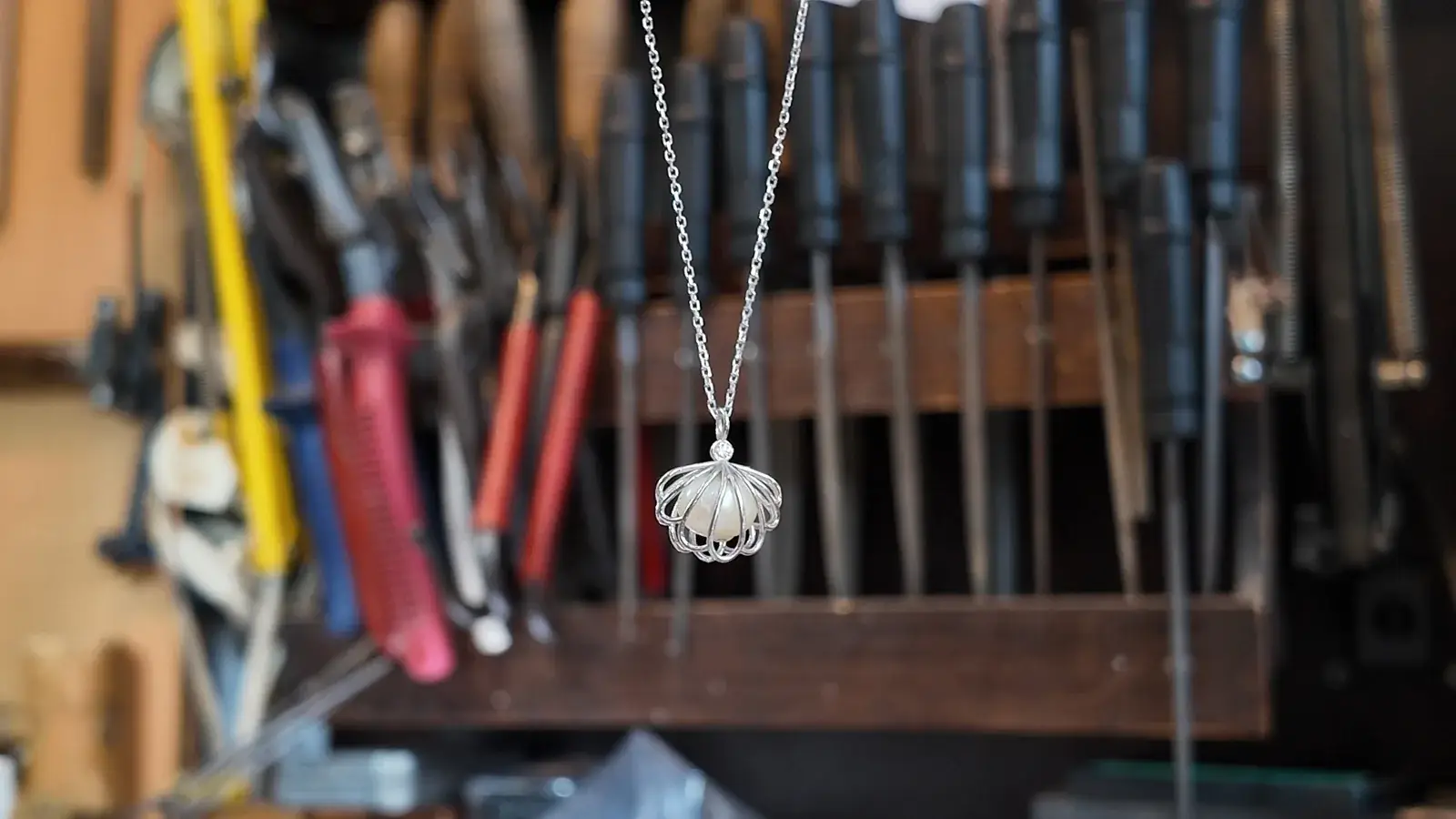 Openwork pendant necklace hanging in front of tools at Bamina’s workbench