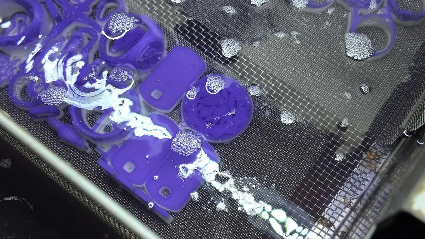 Purple jewelry patterns in a mesh tray beneath liquid and bubbles